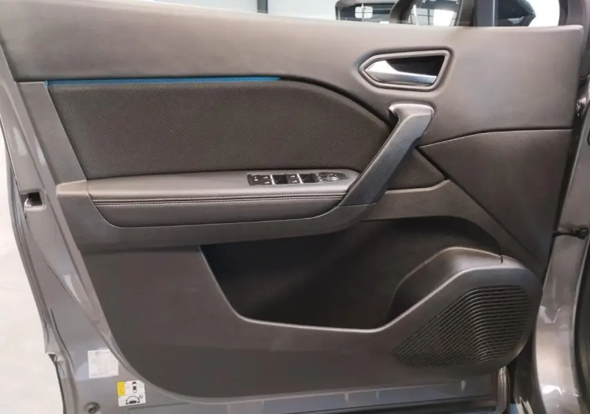 Gros plan sur la porte avant gauche du Renault Symbioz 2025 gris Cassiopée avec commandes de vitres et haut-parleur intégré.