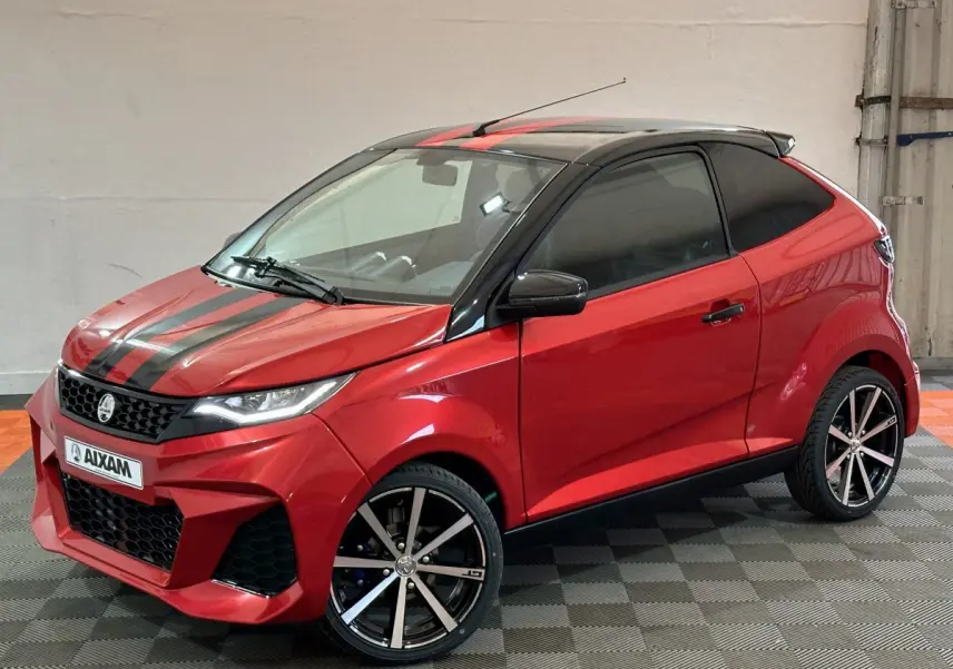 Vue 3/4 avant droite d'une Aixam Ambition rouge 2026 avec bandes noires sur capot et jantes alliage noires.