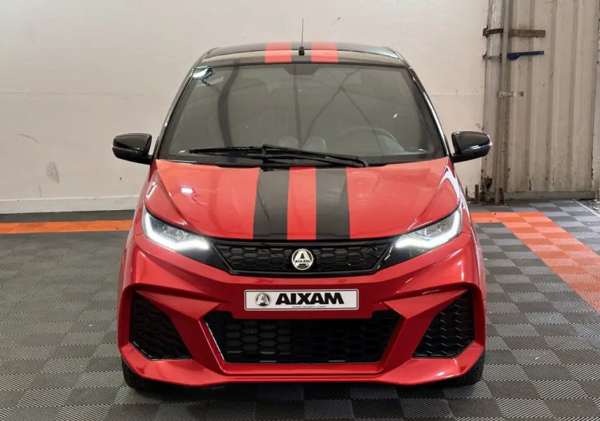 Vue avant d'une Aixam Ambition 0.5 City Coupe GTI rouge avec bandes noires et rétroviseur caméra côté conducteur.