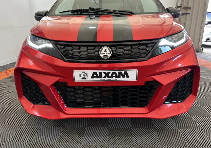 Vue avant rapprochée de l'Aixam Ambition rouge 2026 avec bandes noires et calandre hexagonale distinctive.