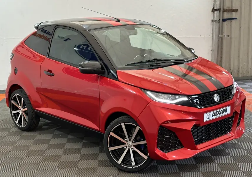 Vue 3/4 avant droite de l'AIXAM AMBITION 0.5 CITY COUPE GTI rouge avec bandes noires et jantes alliage.