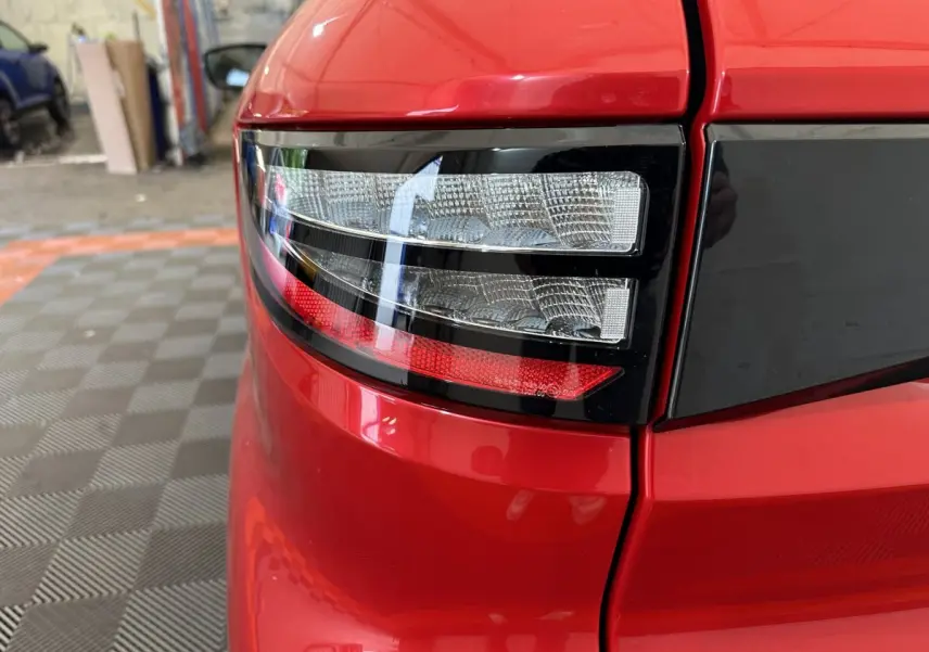 Gros plan sur le feu arrière gauche rouge brillant de l'AIXAM AMBITION 0.5 CITY COUPE GTI E5+ 2026 avec bande noire.