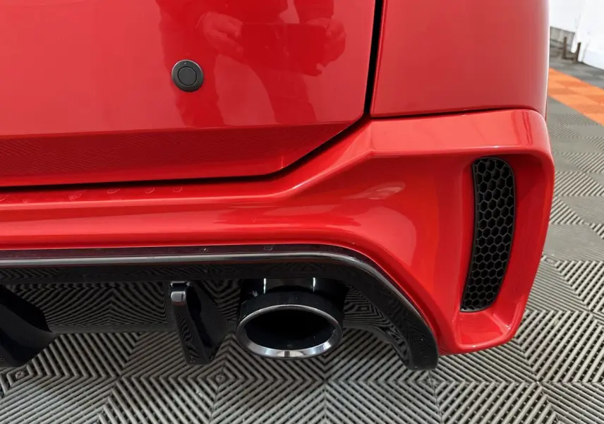 Gros plan sur l'arrière droit rouge d'une Aixam Ambition 0.5 City Coupe GTI 2026 avec sortie d'échappement et diffuseur noir.