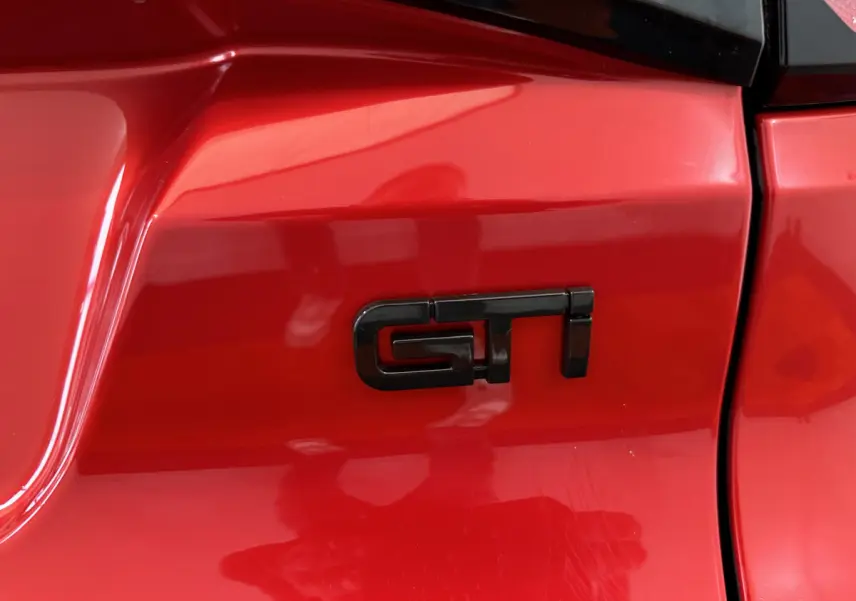 Gros plan sur l’inscription GTI noire sur la carrosserie rouge vif de l’AIXAM AMBITION 0.5 CITY COUPE GTI E5+ 2026.