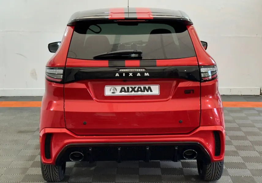 Vue arrière d'une Aixam Ambition rouge 2026 avec bande noire centrale et logo GTI sur fond clair.
