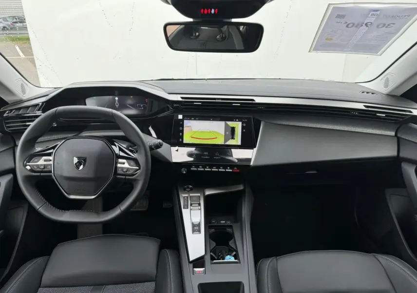 Intérieur avant du Peugeot 308 SW 2024, tableau de bord noir avec écran tactile et volant compact au design moderne.