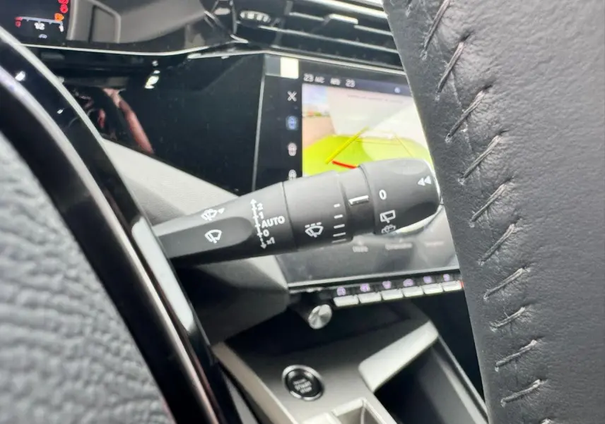Gros plan sur la commande d'essuie-glace et l'écran tactile affichant la caméra de recul dans l'habitacle du Peugeot 308 SW blanc.