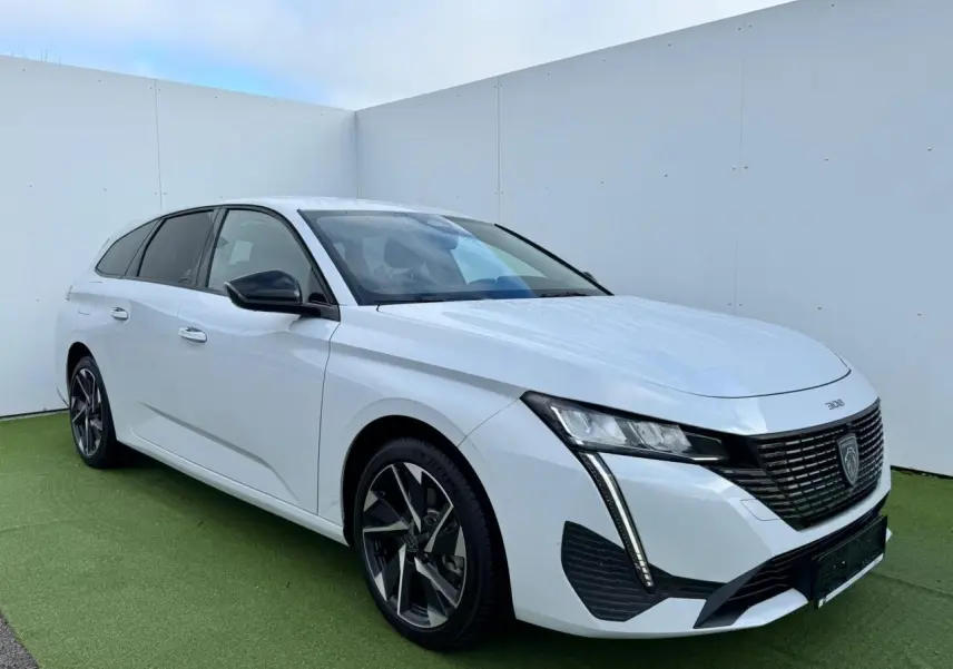 Peugeot 308 SW blanc Okenite vue 3/4 avant droit avec calandre noire et jantes alliage 17 pouces Halong diamantées.