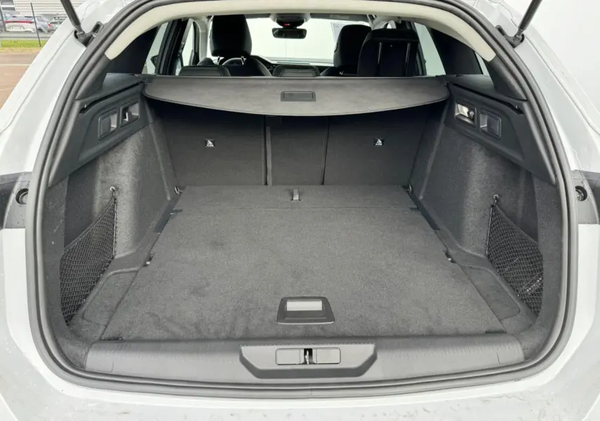 Coffre ouvert d'une Peugeot 308 SW blanche, vue arrière montrant un espace de chargement spacieux et bien agencé.