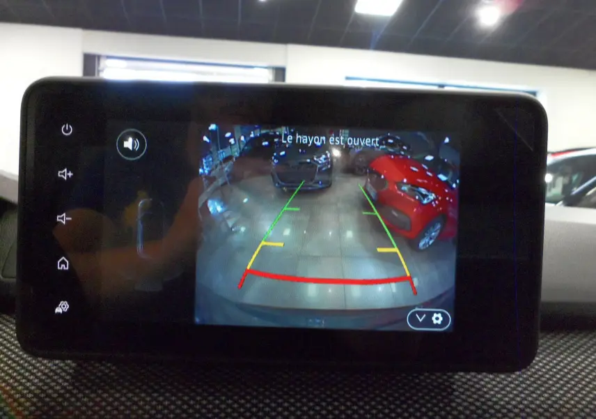 Écran de caméra de recul du Dacia Jogger TCe 110 vert cèdre montrant l'arrière en intérieur avec voitures garées.