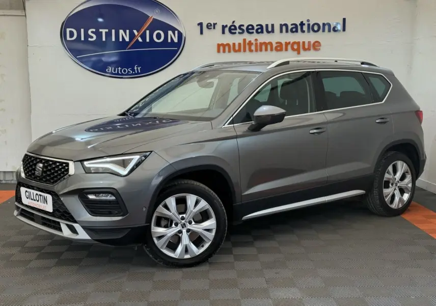 SEAT Ateca gris clair vue de profil côté gauche, avec jantes alliage et barres de toit chromées visibles.