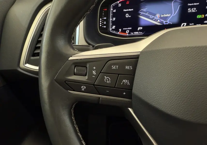 Vue rapprochée du volant cuir noir du SEAT Ateca 2023, avec commandes de régulateur et affichage numérique du tableau de bord.