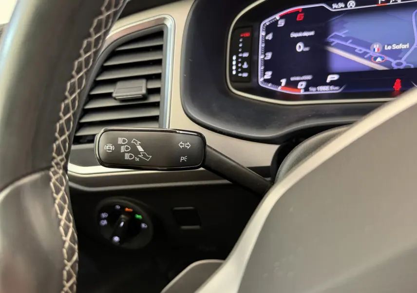 Gros plan sur la manette de clignotant à gauche du volant dans le tableau de bord numérique du SEAT Ateca gris clair 2023.