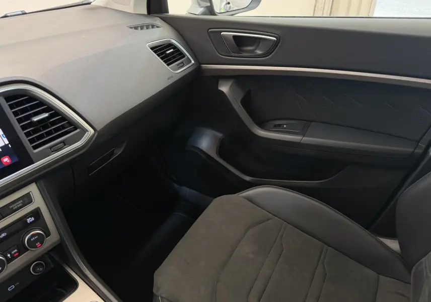Vue intérieure côté passager du SEAT Ateca 2023, montrant siège en tissu gris et tableau de bord noir avec écran tactile.