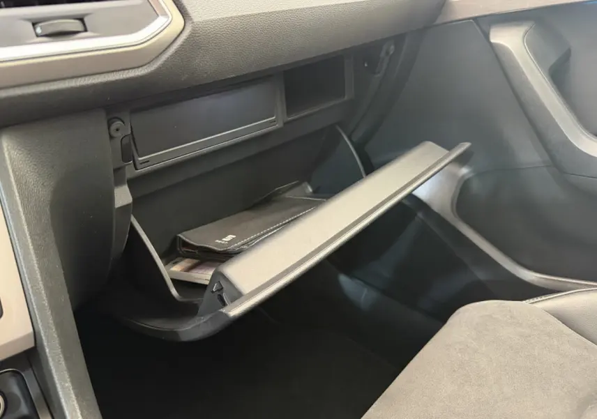 Gros plan de la boîte à gants ouverte côté passager dans l'habitacle noir du SEAT Ateca gris clair 2023.
