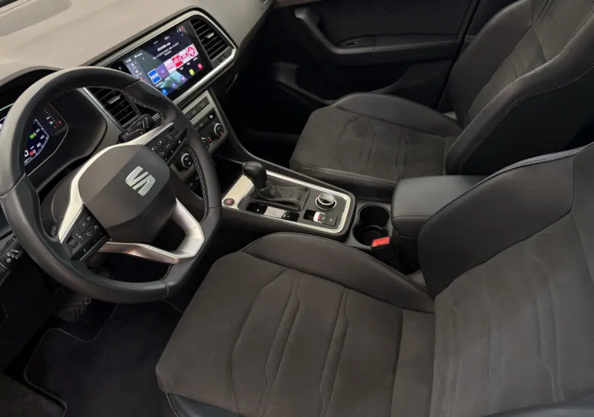 Intérieur noir du SEAT Ateca 2023 vu côté conducteur, avec volant multifonction et écran tactile central.