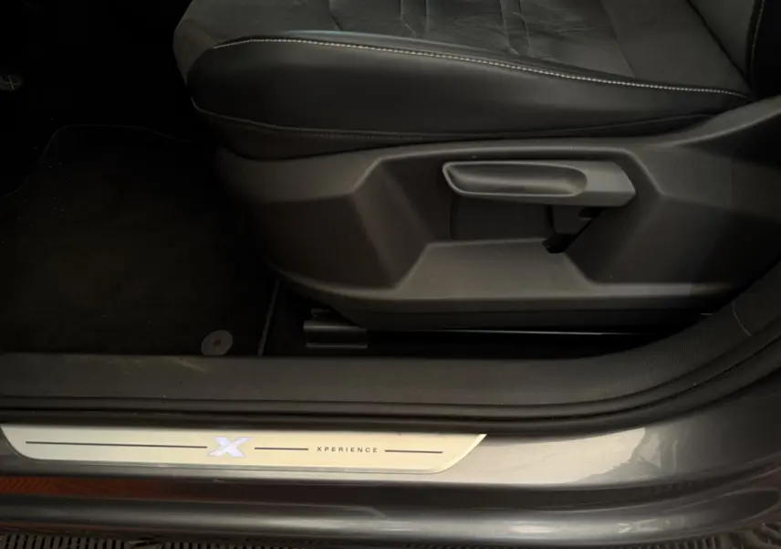 Détail de la porte côté conducteur d'un SEAT Ateca gris clair 2023 avec seuil Xperience éclairé et siège noir.