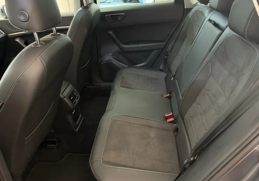 Vue intérieure côté droit des sièges arrière en cuir noir du SEAT Ateca gris clair 2023 avec surpiqûres blanches.