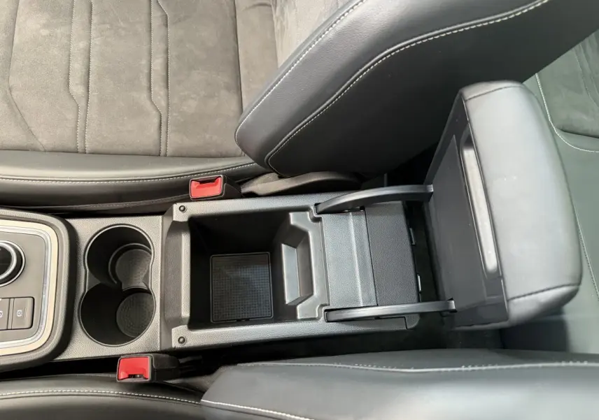 Gros plan sur la console centrale noire avec accoudoir relevé et porte-gobelets du SEAT Ateca gris clair 2023.