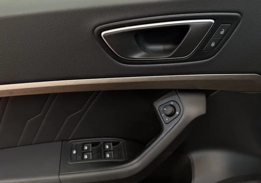 Gros plan sur la porte côté conducteur du SEAT Ateca gris clair, montrant la poignée, commandes vitres et réglage rétroviseurs.