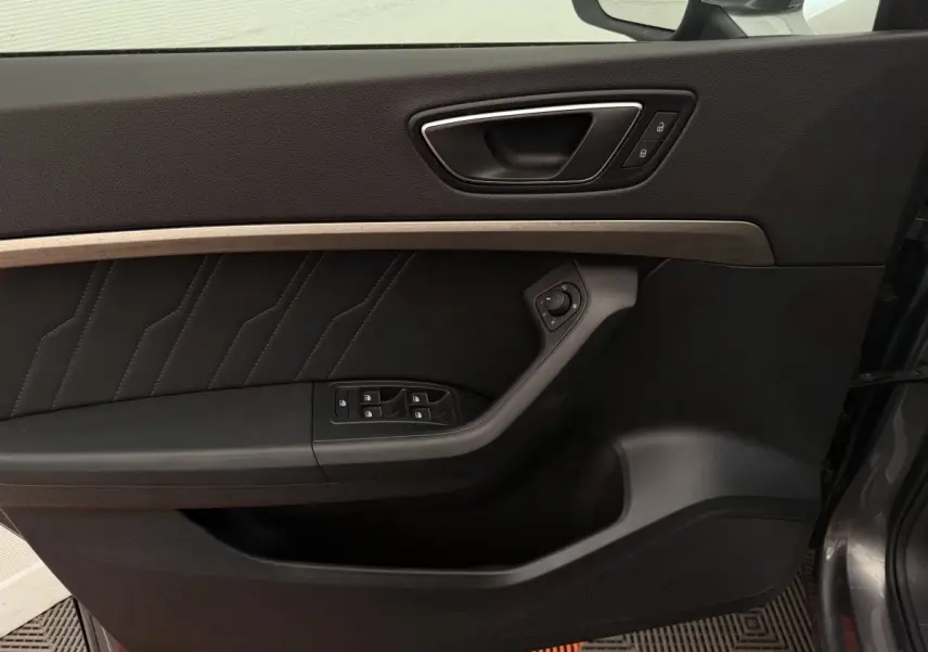 Gros plan sur la porte avant gauche noire avec insert bois clair et commandes électriques de la SEAT Ateca 2023.