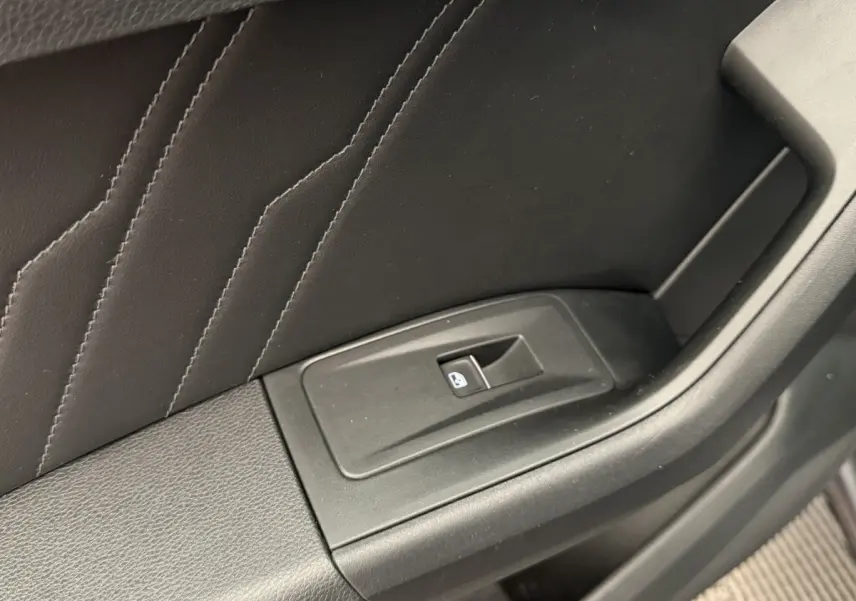 Gros plan sur le bouton de verrouillage des vitres sur la porte intérieure noire du SEAT Ateca gris clair 2023