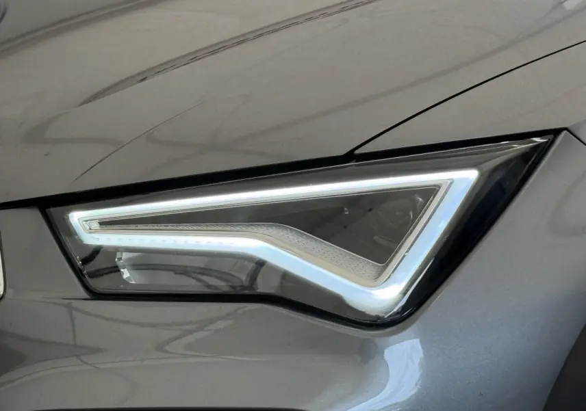 Gros plan sur le phare avant droit LED du SEAT Ateca gris clair 2023 avec contour lumineux distinctif en forme de flèche.