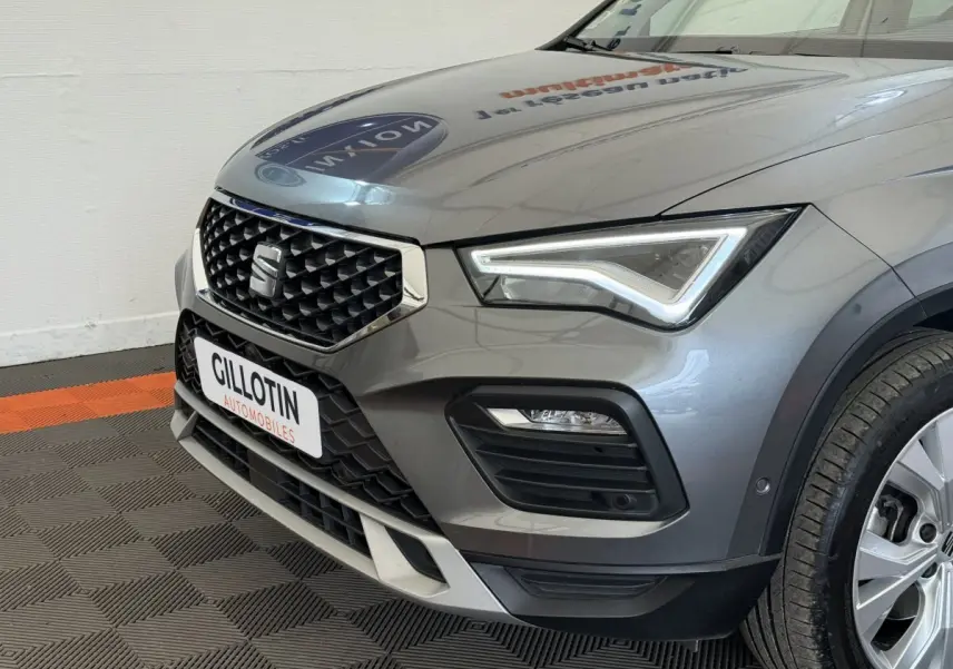 Vue 3/4 avant droit d'un SEAT Ateca gris clair avec calandre noire et phares LED distinctifs.