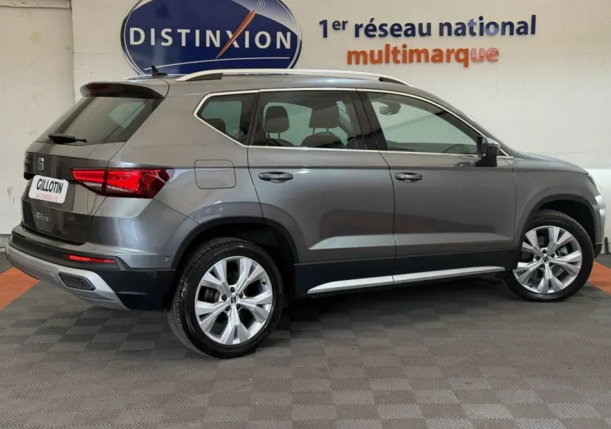 Vue latérale droite d'un SEAT Ateca gris clair 2023 garé en intérieur avec jantes alliage et toit ouvrant.