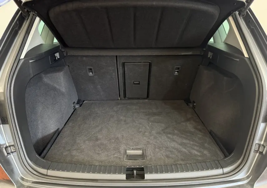 Coffre ouvert gris clair du SEAT Ateca 2023, vue intérieure montrant l'espace de chargement et la trappe centrale.