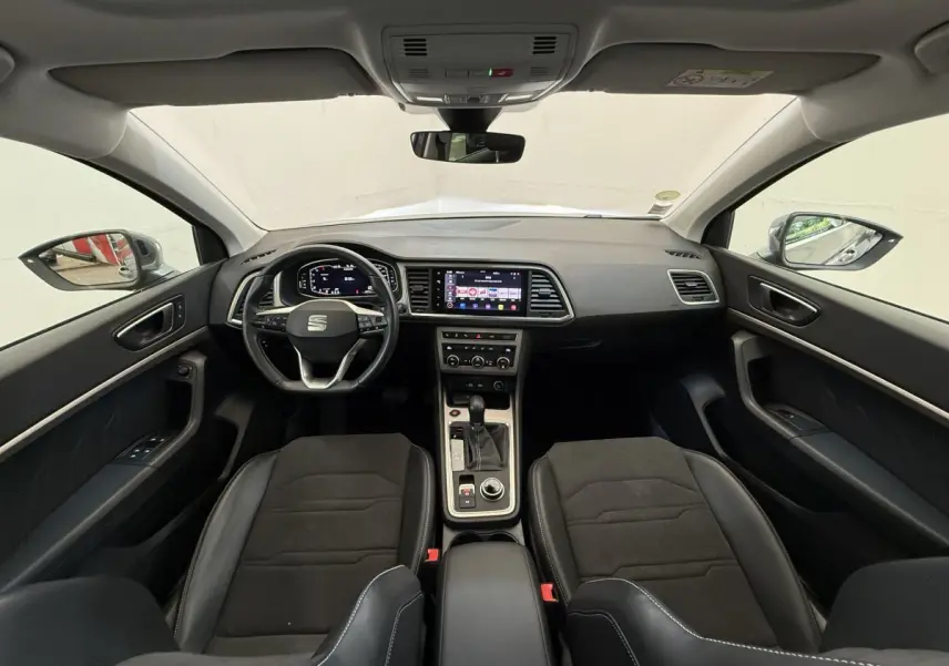 Vue intérieure avant du SEAT Ateca 2023 avec tableau de bord noir, écran tactile central et volant multifonctions.
