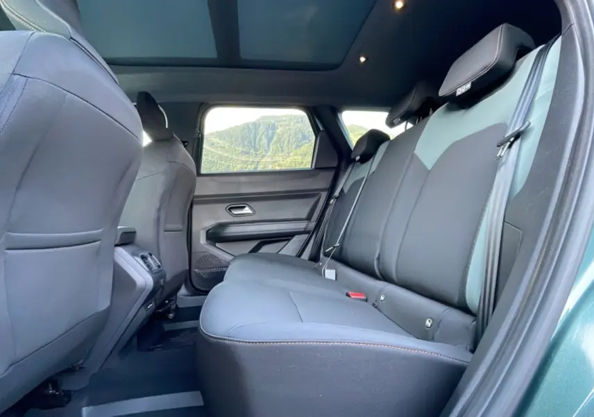 Vue intérieure arrière côté droit du Dacia Bigster 2025 vert cèdre, montrant les sièges arrière et la porte ouverte.