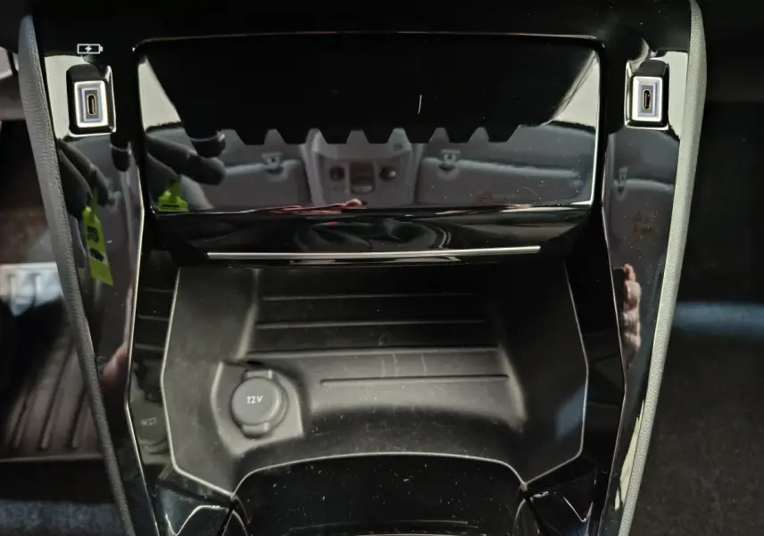 Gros plan sur la console centrale noire brillante de la Peugeot 208 PureTech 100 S&S Allure 2025.