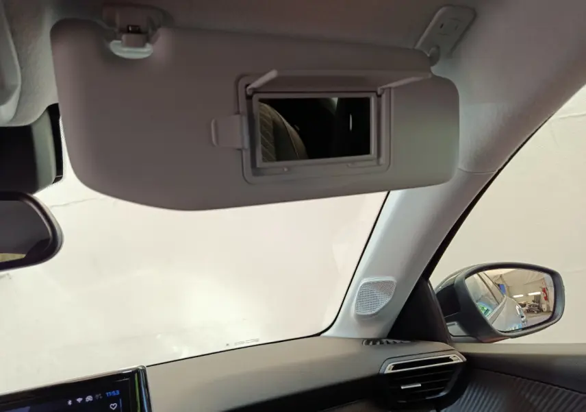 Détail intérieur du pare-soleil avec miroir ouvert et rétroviseur côté droit dans une Peugeot 208 gris clair.