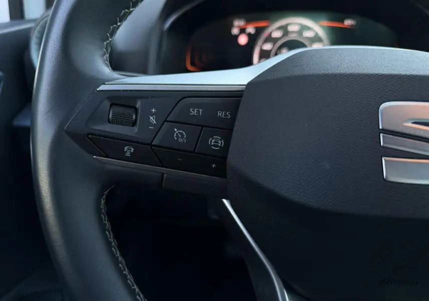 Gros plan sur la partie gauche du volant noir de la SEAT Arona 2025 avec commandes de régulateur et aide à la conduite.