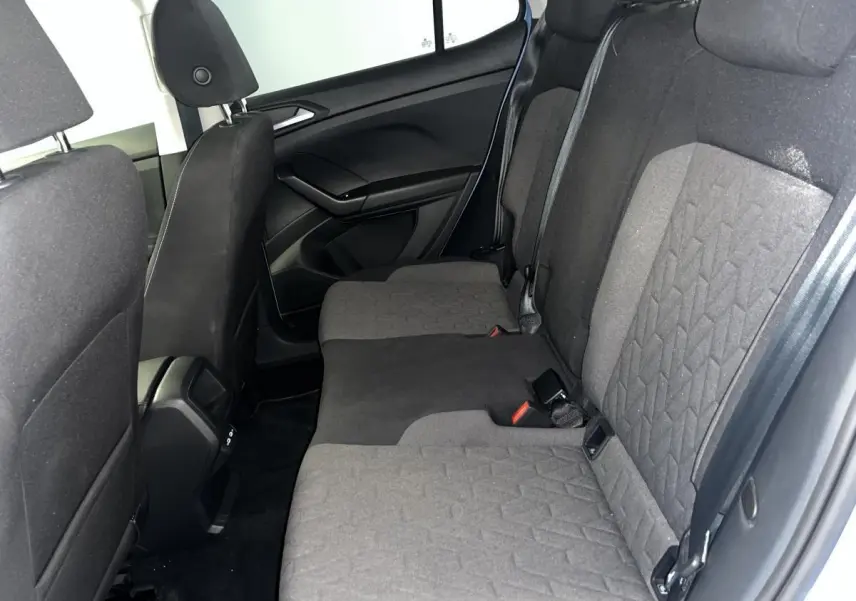 Vue latérale intérieure montrant la banquette arrière en tissu gris du Volkswagen T-Cross 2024 avec vitres surteintées.