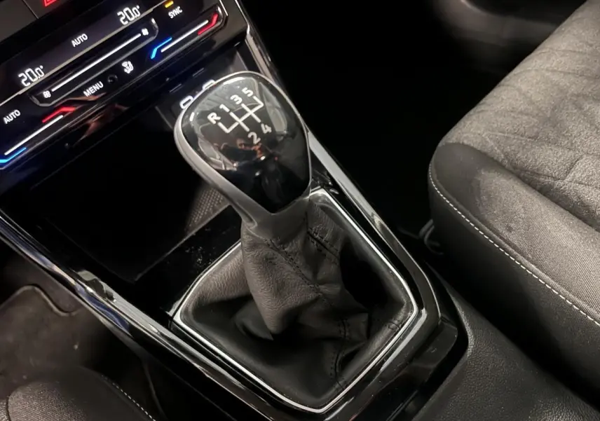 Le levier de vitesses manuel en cuir noir du Volkswagen T-Cross 2024, avec console centrale et siège tissu gris.