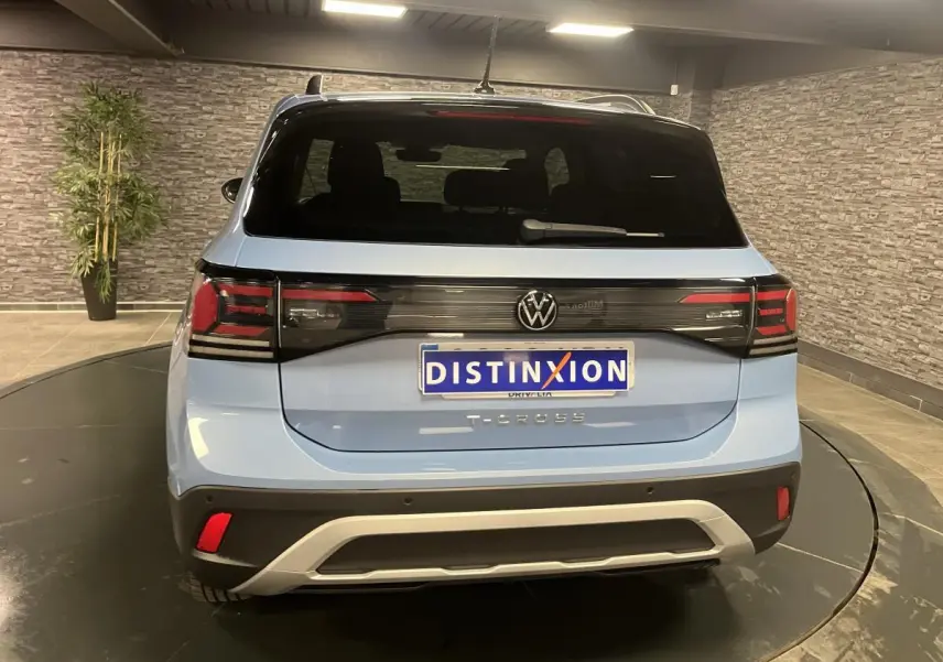 Vue arrière d'un Volkswagen T-Cross bleu clair 2024 avec feux arrière LED et lunette arrière surteintée.
