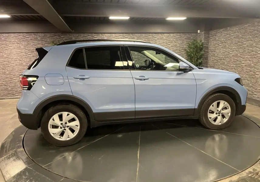 Profil côté gauche d'un Volkswagen T-Cross bleu clair 2024, avec vitres arrière surteintées et jantes alliage argent.