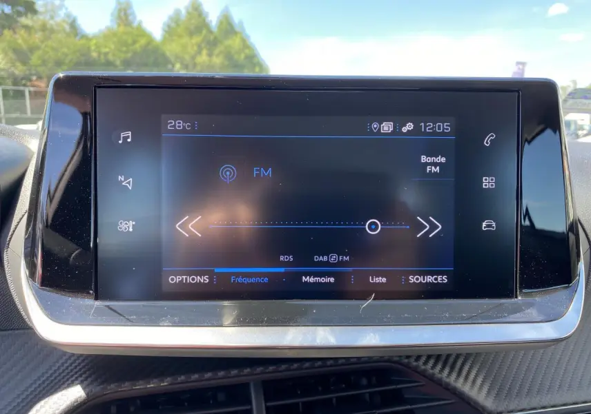 Écran tactile central du tableau de bord du Peugeot 2008 2021 affichant la radio FM en extérieur lumineux