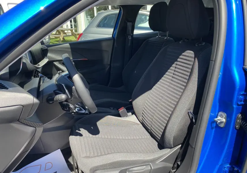 Intérieur du Peugeot 2008 2021 bleu, vue côté conducteur ouverte, sièges tissu gris et tableau de bord moderne.