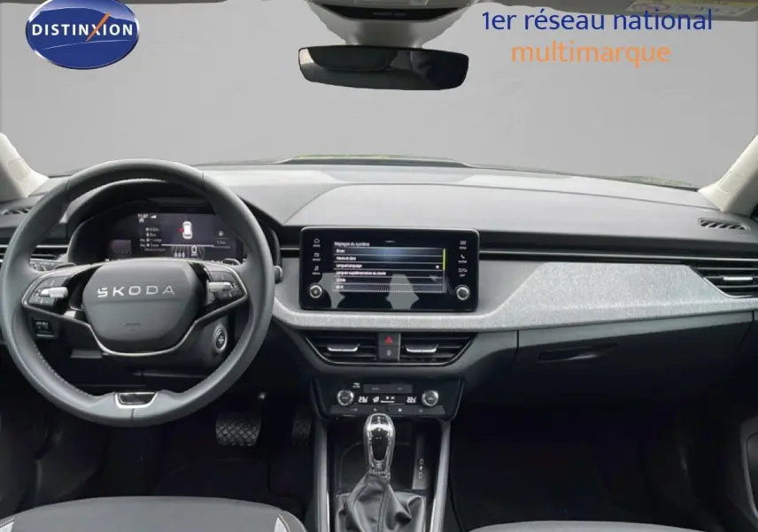 Vue intérieure frontale du tableau de bord gris et noir du Skoda Kamiq 2025 avec écran tactile et volant multifonction.