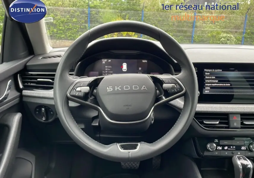 Vue intérieure centrée sur le volant SKODA noir, avec tableau de bord digital et écran tactile du KAMIQ 2025.