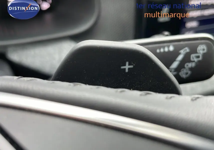 Gros plan sur la palette de changement de vitesse "+" derrière le volant en cuir noir du Skoda Kamiq gris graphite.