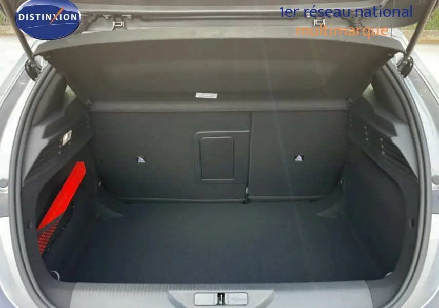 Coffre ouvert vu de l'arrière d'une Peugeot 308 gris Artense métal, avec rangement latéral et tapis noir.