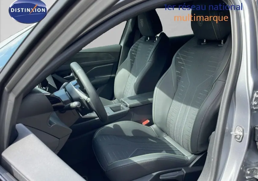 Vue intérieure côté conducteur de la Peugeot 308 gris Artense, sièges en tissu noir avec surpiqûres contrastées.