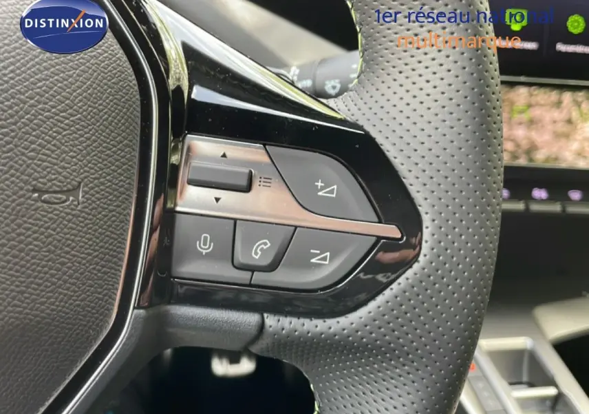 Gros plan sur le volant perforé de la Peugeot 308 gris Artense, avec commandes intégrées visibles côté gauche.