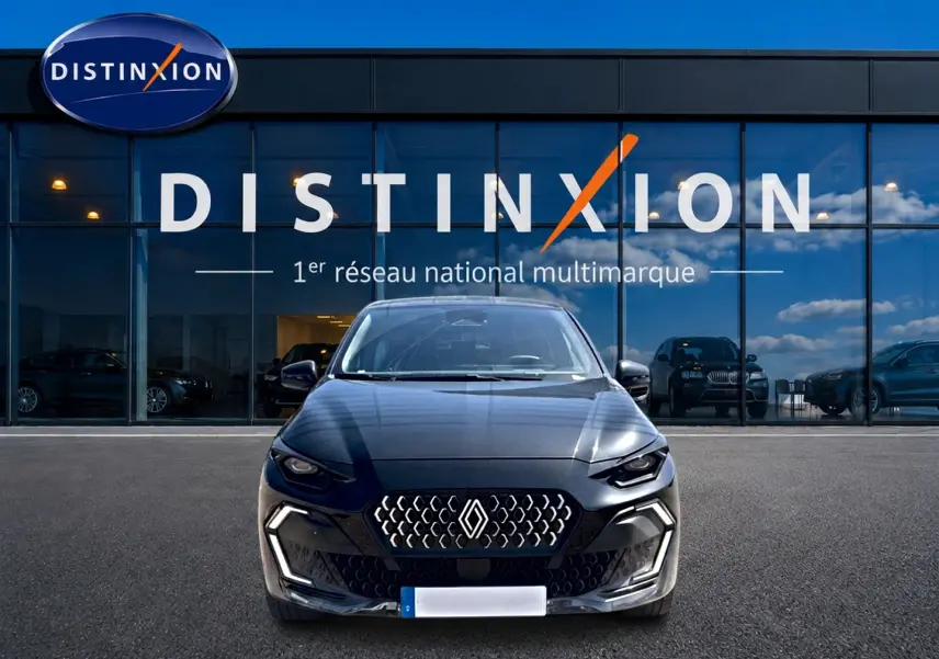 Vue frontale d'une Renault Clio VI noire 2026 avec calandre distinctive et phares LED devant un showroom Distinxion.
