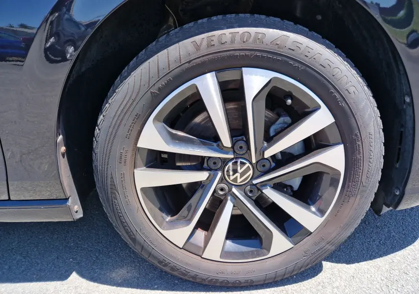 Gros plan sur la roue avant gauche noire métallisée d'une Volkswagen Golf VIII avec jante alliage bicolore.