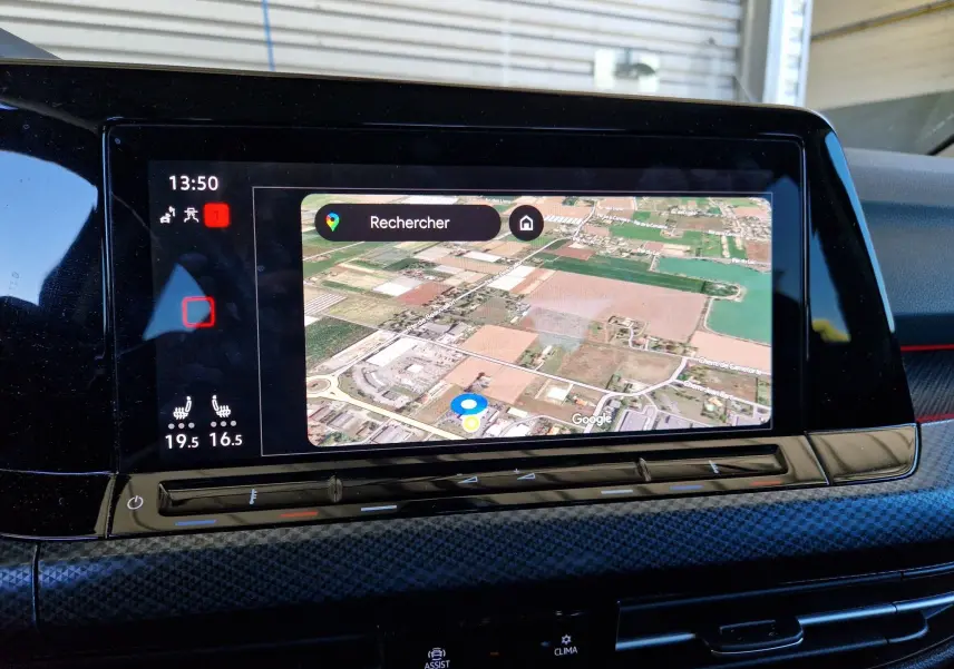 Écran tactile central de la Volkswagen Golf VIII noir, affichant la navigation par satellite avec vue aérienne des environs.